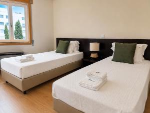 two beds in a bedroom with a window at Dona Emília Mercado in Viana do Castelo