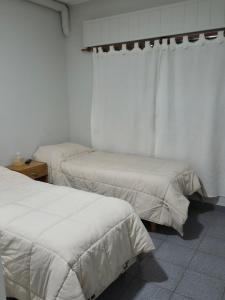 two beds in a room with white walls at Tortugas Hotel in Carlos Casares