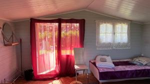 a bedroom with red curtains and a bed and a window at Peipsi Village Sofia in Kasepää