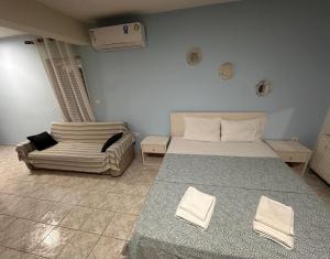 a bedroom with a bed and a couch in it at Bluesky Apartment AXD in Alexandroupoli