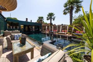 an outdoor patio with a pool with chairs and a table at Crazy Bear Beaconsfield in Beaconsfield