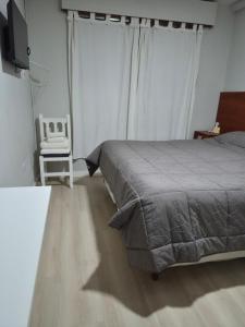 a bedroom with a bed and a chair next to a window at Tortugas Hotel in Carlos Casares