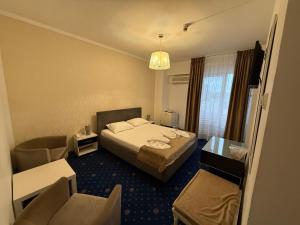 a hotel room with a bed and a chair at Dallin Center Hotel in Bucharest +5 photos