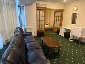 a living room with a leather couch and a table at Dallin Center Hotel in Bucharest