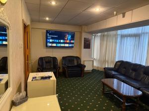 a waiting room with a couch and chairs and a tv at Dallin Center Hotel in Bucharest