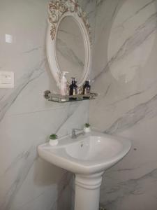 a white bathroom with a sink and a mirror at Sunrise Bay Villa in Mahébourg