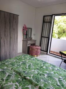 a bedroom with a green bed and a large window at Sunrise Bay Villa in Mahébourg
