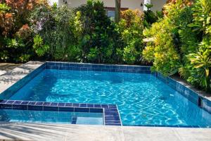 a swimming pool in a garden with plants at Bustan Inn in Kilima Juu Pwani