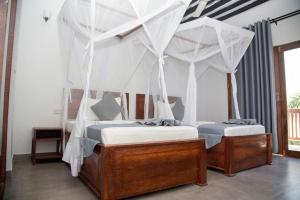 two beds in a room with mosquito nets at Bustan Inn in Kilima Juu Pwani