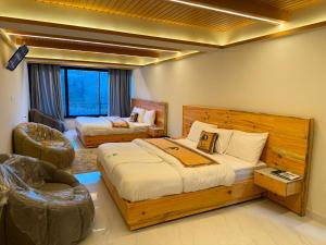 a bedroom with a bed and a chair in it at Pine View Hotel in Abbottabad