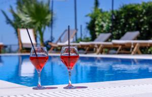 two glasses of red wine sitting on a table near a pool at Agroturizem Bylis in Hekal