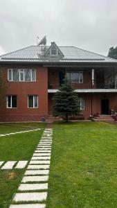 a large red brick building with a grass yard at Пар&Речка in Almaty