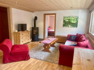 a living room with a red couch and a table at Chalet Floriana in Les Diablerets