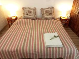 a bed with a striped blanket with a pair of scissors on it at Le havre du voyageur in Charly