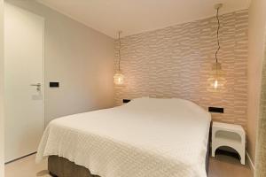 a bedroom with a white bed and two lights at Prinsenhof 10 - Ouddorp in Ouddorp +32 photos