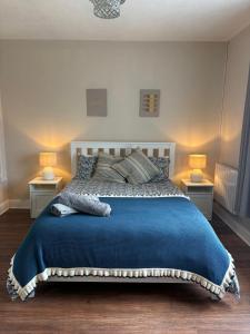 a bedroom with a large blue bed with two lamps at Teach Duff in Clonmany