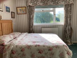 a bedroom with a bed with a floral bedspread and a window at Room with a View in Grantham