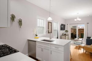 a white kitchen with a sink and a living room at Jennifer's Modern Federal Hill Apt w Private Deck in Providence