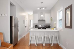a kitchen with white cabinets and a kitchen island with bar stools at Jennifer's Modern Federal Hill Apt w Private Deck in Providence +28 photos