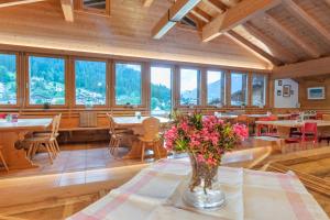 a dining room with tables and chairs and windows at Sport-Lodge Klosters in Klosters