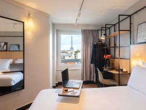 a hotel room with a bed and a laptop on a desk at Ibis Paris Tour Eiffel Cambronne 15ème in Paris +160 photos