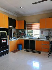 a kitchen with orange and black cabinets and a stove at Villa Cempaka II in Changlun