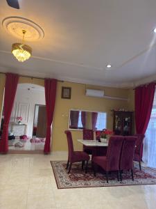 a dining room with red curtains and a table and chairs at Villa Cempaka II in Changlun +5 photos