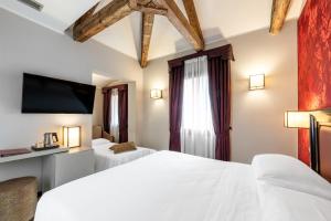 a bedroom with two beds and a flat screen tv at Hotel Paganelli in Venice