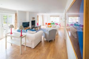 a living room with white couches and a tv at Flint Cottage, Brancaster in Brancaster