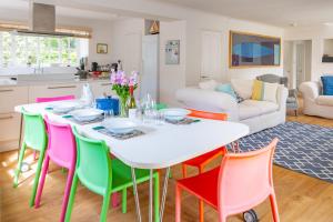 a dining room with a white table and colorful chairs at Flint Cottage, Brancaster in Brancaster