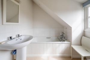 a white bathroom with a sink and a bath tub at Flint Cottage, Brancaster in Brancaster +23 photos