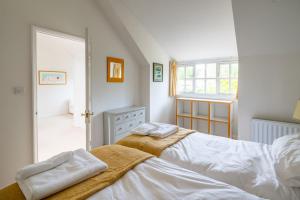 a bedroom with two beds and a window at Flint Cottage, Brancaster in Brancaster