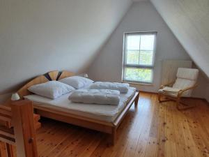 a bedroom with a bed and a chair and a window at Ruhige, moderne Maisonette Ferienwohnung Rügensonne mit großem Balkon - umgeben vom Wasser in Breege