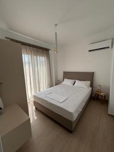 a bedroom with a large bed and a window at Almira Suites by the sea 3 in Áyios Dhimítrios