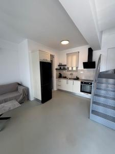 a white kitchen with a black refrigerator in a room at Almira Suites by the sea 3 in Áyios Dhimítrios