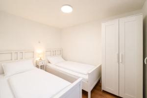 a white bedroom with two beds and a closet at Ferienhaus am Strand 88 - Bade- & Saunawelt täglich inklusive in Baabe
