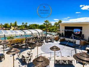 a patio with tables and umbrellas in front of a pool at Le Cocon Mobil Home à 150 m de la plage Camping 5 Etoiles Les Dunes Parc Aquatique in Torreilles