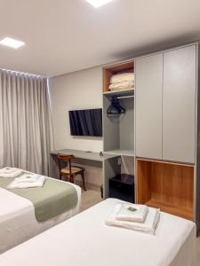 a hotel room with two beds and a desk at Uai Hotel Jaíba in Terra Fôfa