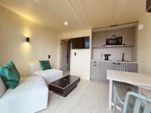 a living room with a white couch and a kitchen at Filao - Clim Piscine in Auch