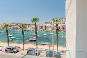 a view of a harbor with palm trees and boats at C'est La Vie Hotel Marsascala in Marsaskala