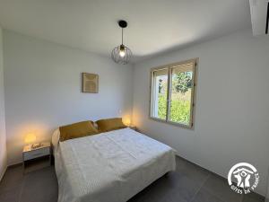a white bedroom with a bed and a window at Le canigou in Fuilla