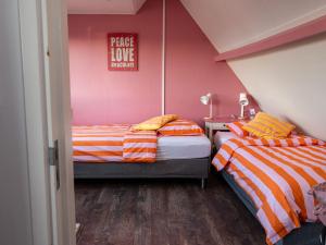 two twin beds in a room with pink walls at Slapen bij Ticho in Yerseke