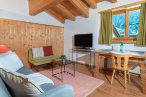 a living room with a couch and a table and a television at Sport-Lodge Klosters in Klosters