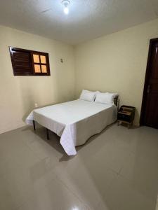 a bedroom with a large white bed with a window at Aconchego da serra no centro de Pacoti in Pacoti