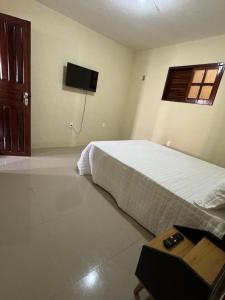 a bedroom with a bed and a tv on the wall at Aconchego da serra no centro de Pacoti in Pacoti