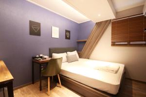 a bedroom with a bed and a desk with a chair at 벨린 호텔 in Kŏje