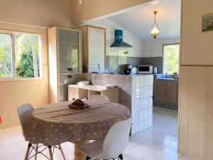 a kitchen with a table and chairs and a kitchen with a table and a table at Maison de charme avec vue sur mer à Bas Vent - Confort optimal in Bas Vent
