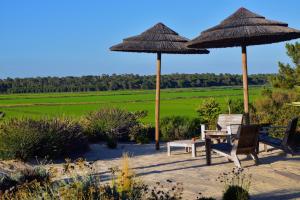 a patio with two umbrellas and a table and chairs at Casa Atlântico Carvalhal Comporta, apartamento piscina aquecida in Carvalhal