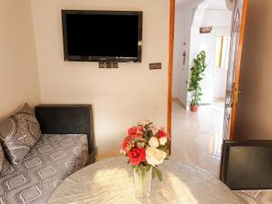 a vase of flowers sitting on a table with a tv at Modern apartment near Oujda - 80 m² - 8 guests in Oujda +13 photos