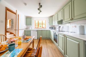 a kitchen with green cabinets and a wooden table at Acorn House in Briston